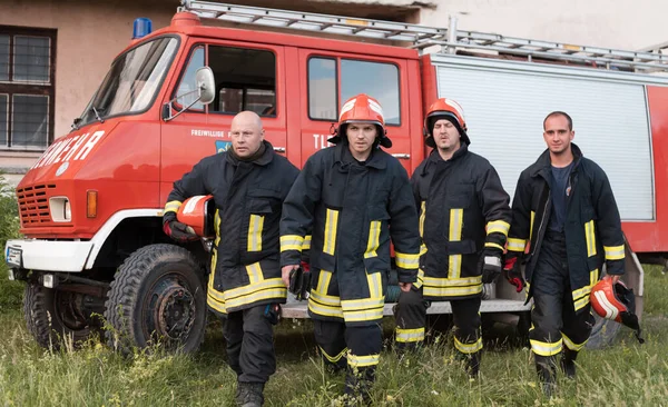 Group of fire fighters standing confident after a well done rescue operation. Firemen ready for emergency service. High quality photo