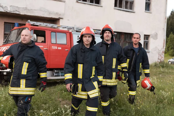 Group of fire fighters standing confident after a well done rescue operation. Firemen ready for emergency service. High quality photo