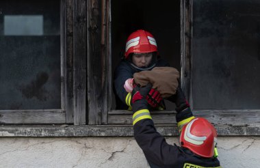 İtfaiyeci kahraman yangından sonra bebeğini yanan binadan dışarı taşıyor. İnsanları tehlikeli bir yerden kurtarmak. Takım çalışması Yüksek kalite fotoğraf