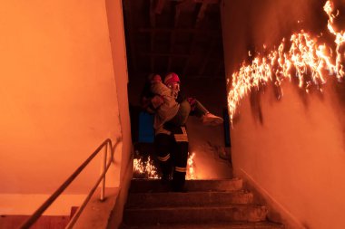 Cesur İtfaiyeci Yanan Binanın Merdivenlerinden İndi ve Kurtarılmış Kızı Kollarında Tuttu. Ateş açın ve arka planda bir itfaiyeci var. Yüksek kalite fotoğraf