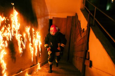 Cesur İtfaiyeci yukarı çıkıp yanan bir binadaki insanları kurtarıyor. Ateş ve ateş açın. Düşük ışık seçici odak fotoğrafı.. 