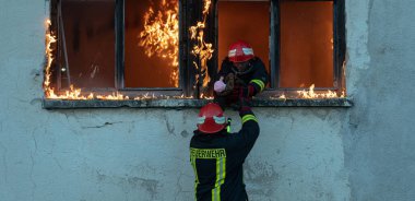 İtfaiyeci kahraman yangından sonra bebeğini yanan binadan dışarı taşıyor. İnsanları tehlikeli bir yerden kurtarmak. Takım çalışması Yüksek kalite fotoğraf