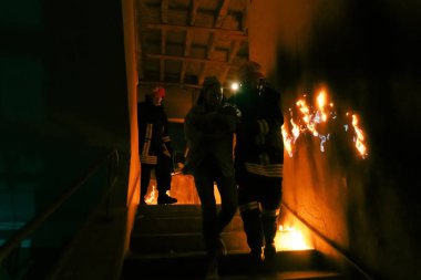 Cesur İtfaiyeci Yanan Binanın Merdivenlerinden İndi ve Kurtarılmış Kızı Kollarında Tuttu. Ateş açın ve arka planda bir itfaiyeci var. Yüksek kalite fotoğraf