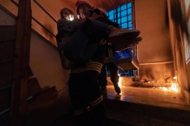 Cesur İtfaiyeci Yanan Binanın Merdivenlerinden İndi ve Kurtarılmış Kızı Kollarında Tuttu. Ateş açın ve arka planda bir itfaiyeci var. Yüksek kalite fotoğraf