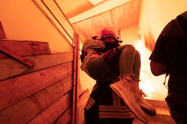 Cesur İtfaiyeci Yanan Binanın Merdivenlerinden İndi ve Kurtarılmış Kızı Kollarında Tuttu. Ateş açın ve arka planda bir itfaiyeci var. Yüksek kalite fotoğraf