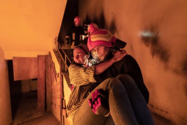 Cesur İtfaiyeci Yanan Binanın Merdivenlerinden İndi ve Kurtarılmış Kızı Kollarında Tuttu. Ateş açın ve arka planda bir itfaiyeci var. Yüksek kalite fotoğraf