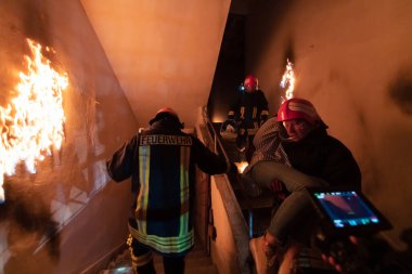 Cesur İtfaiyeci Yanan Binanın Merdivenlerinden İndi ve Kurtarılmış Kızı Kollarında Tuttu. Ateş açın ve arka planda bir itfaiyeci var. Yüksek kalite fotoğraf