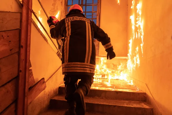 Brave Fireman going upstairs to save and rescue people in a Burning Building. Open fire and flame. Low light hi is selective focus stock photo.