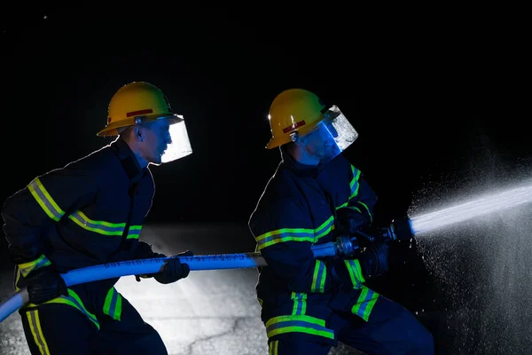 消防士は 火災の危険性を排除するために水ホースを使用します 危険な救助任務で消防士のチーム 高品質の写真 — ストック写真