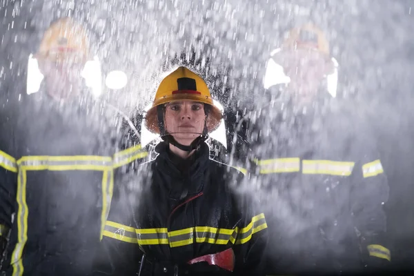一组消防员站在一起 勇敢而乐观地行走 由一位女性担任组长的形象 大雨是好运或消防员对汽车救援的概念 高质量的照片 — 图库照片