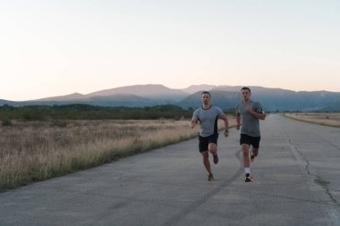 Genç sporcu adamlar güneşli bir sabahta şehirde koşuyorlar. Yüksek kalite fotoğraf