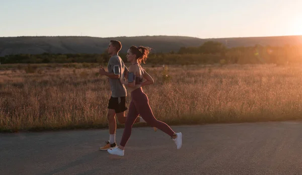 healthy young couple jogging in the city streets in the early morning with a beautiful sunrise in the background. High quality photo