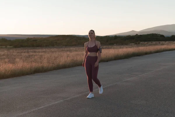 早朝街をジョギングする健康な若い女性背景に美しい日の出と 高品質の写真 — ストック写真