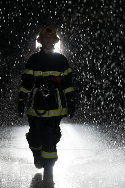 Portrait of a female firefighter standing and walking brave and optimistic. Heavy rain is good luck or firefighters for car rescue concept. High quality photo