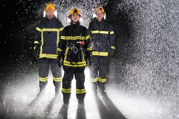 Portrait of a group of firefighters standing and walking brave and optimistic with a female as team leader. Heavy rain is good luck or firefighters for car rescue concept. High quality photo