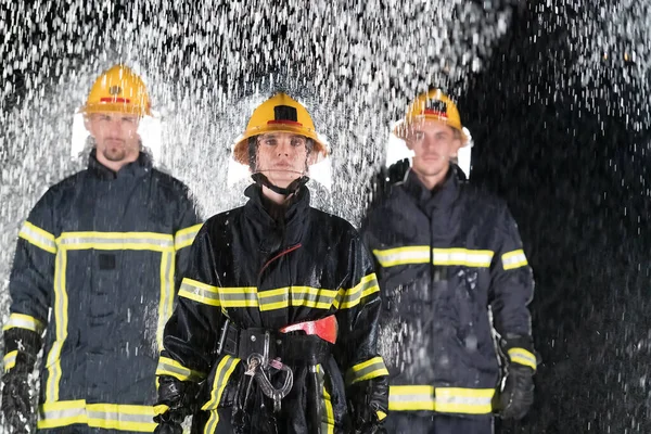 Portrait of a group of firefighters standing and walking brave and optimistic with a female as team leader. Heavy rain is good luck or firefighters for car rescue concept. High quality photo