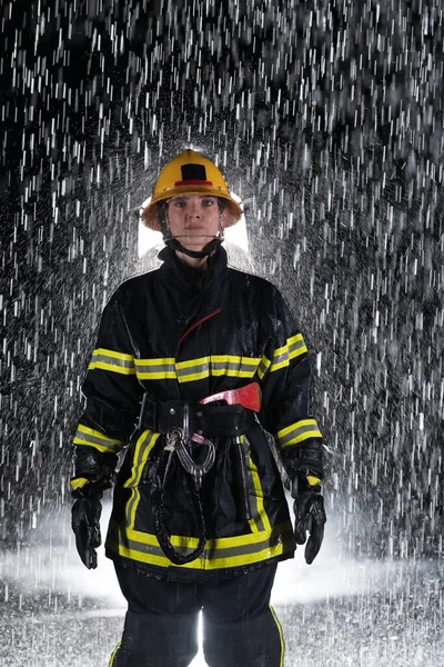 Portrait of a female firefighter standing and walking brave and optimistic. Heavy rain is good luck or firefighters for car rescue concept. High quality photo