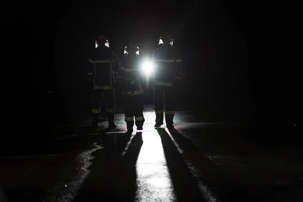一组消防员站在一起 勇敢而乐观地行走 由一位女性担任组长的形象 大雨是好运或消防员对汽车救援的概念 高质量的照片 — 图库照片