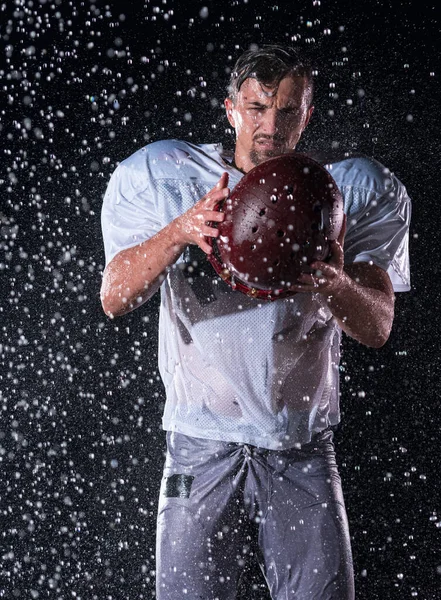 站在球场上的美国足球运动员勇士举着他的头盔准备比赛 准备跑 进攻和得分触地得分的玩家 雨夜与戏剧性镜头耀斑和雨滴 — 图库照片