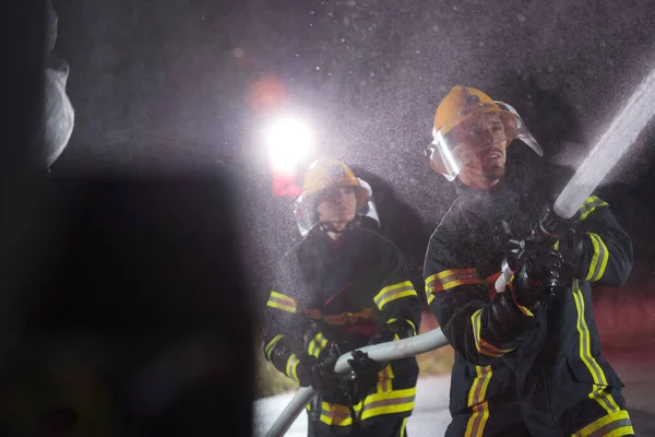 Palomiehet Käyttävät Vesiletkua Palovaaran Poistamiseen Nais Miespalomiesten Ryhmä Vaarallisessa Pelastustehtävässä — kuvapankkivalokuva