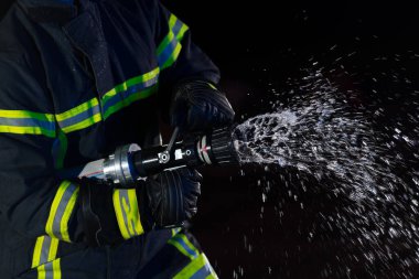 İtfaiyeciler yangın tehlikesini ortadan kaldırmak için su hortumu kullanır. İtfaiyecilerden oluşan bir ekip tehlikeli bir kurtarma görevinde. Yüksek kalite fotoğraf