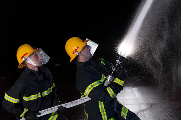 消防员使用水管来消除火灾的危险 救火队正在执行危险的救援任务 高质量的照片 — 图库照片