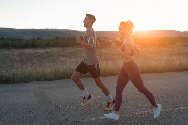 healthy young couple jogging in the city streets in the early morning with a beautiful sunrise in the background. High quality photo