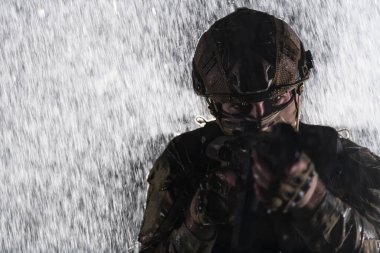 Silahlı asker saldırı tüfeği, plaka taşıyıcısı ve savaş kaskıyla yağmurlu bir gecede tehlikeli bir göreve çıkıyor. Yüksek kalite fotoğraf