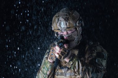 Silahlı asker saldırı tüfeği, plaka taşıyıcısı ve savaş kaskıyla yağmurlu bir gecede tehlikeli bir göreve çıkıyor. Yüksek kalite fotoğraf