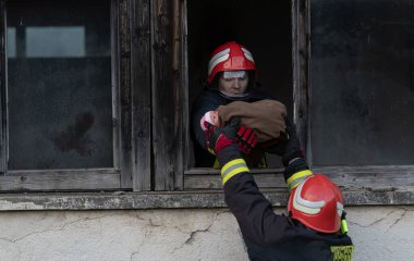 İtfaiyeci kahraman yangından sonra bebeğini yanan binadan dışarı taşıyor. İnsanları tehlikeli bir yerden kurtarmak. Takım çalışması Yüksek kalite fotoğraf