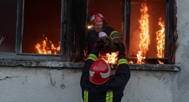 İtfaiyeci kahraman yangından sonra bebeğini yanan binadan dışarı taşıyor. İnsanları tehlikeli bir yerden kurtarmak. Takım çalışması Yüksek kalite fotoğraf