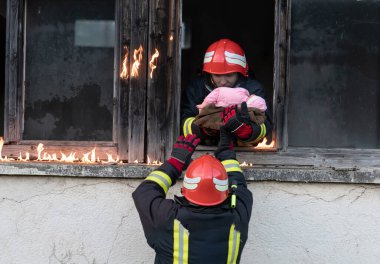 İtfaiyeci kahraman yangından sonra bebeğini yanan binadan dışarı taşıyor. İnsanları tehlikeli bir yerden kurtarmak. Takım çalışması Yüksek kalite fotoğraf