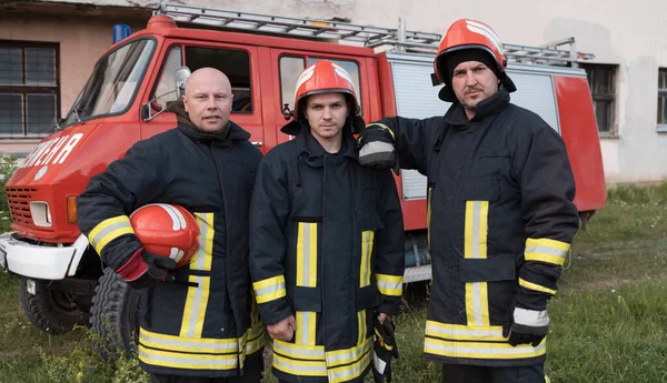 Group of fire fighters standing confident after a well done rescue operation. Firemen ready for emergency service. High quality photo