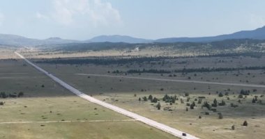 Yazın güneşli bir günde güzel yeşil tarlalarda yol manzarası. Yolunda arabalar olan renkli bir manzara. Üst görünüm, otobanın insansız hava aracından sinematik çekim kurulmasını sağlıyor. 