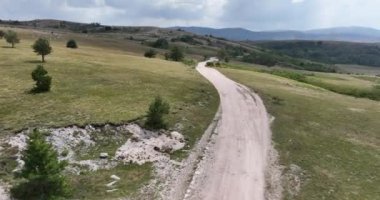 Yazın güneşli bir günde güzel yeşil tarlalarda yol manzarası. Yolunda arabalar olan renkli bir manzara. Üst görünüm, otobanın insansız hava aracından sinematik çekim kurulmasını sağlıyor. 