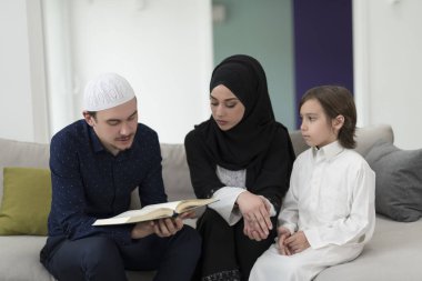 Geleneksel Müslüman ailelerin çocuklu aileleri, evde düzenlenen bir Ramazan ziyafeti sırasında iftar yemeğinden önce Kuran okuyup birlikte dua ediyorlar..