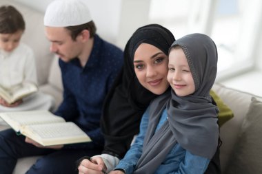 Geleneksel Müslüman ailelerin çocuklu aileleri, evde düzenlenen bir Ramazan ziyafeti sırasında iftar yemeğinden önce Kuran okuyup birlikte dua ediyorlar..