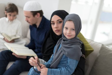 Geleneksel Müslüman ailelerin çocuklu aileleri, evde düzenlenen bir Ramazan ziyafeti sırasında iftar yemeğinden önce Kuran okuyup birlikte dua ediyorlar..