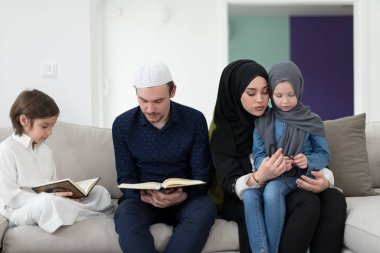 Geleneksel Müslüman ailelerin çocuklu aileleri, evde düzenlenen bir Ramazan ziyafeti sırasında iftar yemeğinden önce Kuran okuyup birlikte dua ediyorlar..