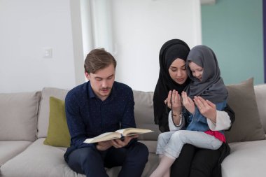 Geleneksel Müslüman ailelerin çocuklu aileleri, evde düzenlenen bir Ramazan ziyafeti sırasında iftar yemeğinden önce Kuran okuyup birlikte dua ediyorlar..
