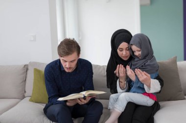 Geleneksel Müslüman ailelerin çocuklu aileleri, evde düzenlenen bir Ramazan ziyafeti sırasında iftar yemeğinden önce Kuran okuyup birlikte dua ediyorlar..