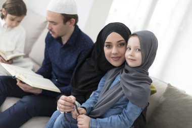Geleneksel Müslüman ailelerin çocuklu aileleri, evde düzenlenen bir Ramazan ziyafeti sırasında iftar yemeğinden önce Kuran okuyup birlikte dua ediyorlar..