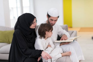 Geleneksel Müslüman ailelerin çocuklu aileleri, evde düzenlenen bir Ramazan ziyafeti sırasında iftar yemeğinden önce Kuran okuyup birlikte dua ediyorlar..