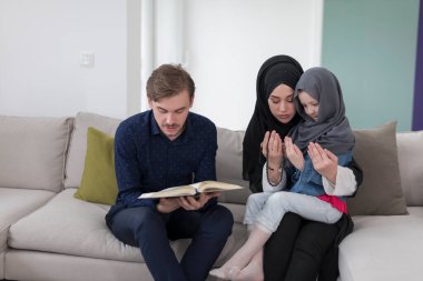 Geleneksel Müslüman ailelerin çocuklu aileleri, evde düzenlenen bir Ramazan ziyafeti sırasında iftar yemeğinden önce Kuran okuyup birlikte dua ediyorlar..