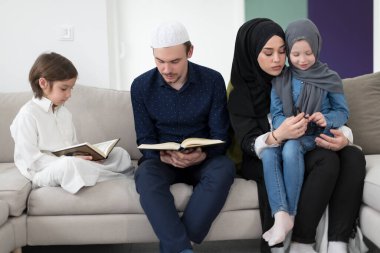 Geleneksel Müslüman ailelerin çocuklu aileleri, evde düzenlenen bir Ramazan ziyafeti sırasında iftar yemeğinden önce Kuran okuyup birlikte dua ediyorlar..