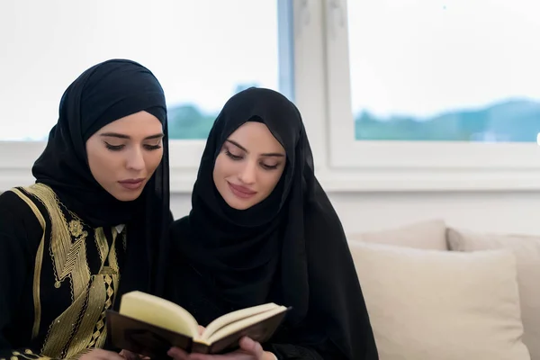在斋月期间 年轻的穆斯林妇女在家里吃花蜜晚餐之前 在沙发上诵读 古兰经 是的高质量的照片 — 图库照片