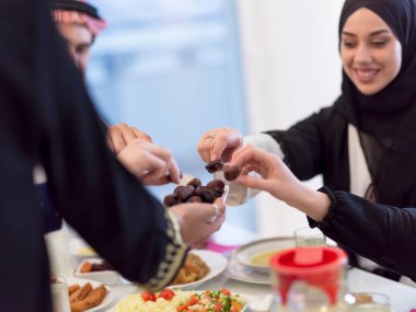 modern çok etnik Müslüman aile bir kase tarihleri paylaşan evde bir ramazan ziyafeti sırasında birlikte iftar yemeği eşliğinde. 