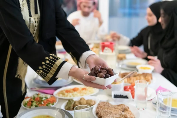 現代の多民族イスラム教徒の家族は 自宅でラマダンのごちそうの間に一緒にイフタールディナーを楽しみながら 日付のボウルを共有します — ストック写真