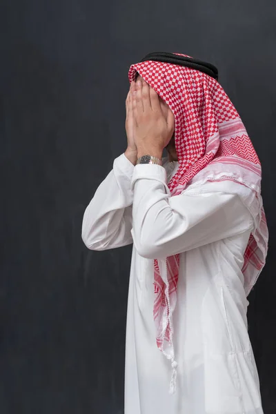 伝統的な衣服で伝統的な祈りを捧げるアラブの若者は 黒い背景の前でジェスチャーを祈ることに手をつないでいます 高品質の写真 — ストック写真