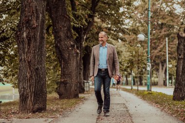 Parkta yürüyen takım elbiseli odaklanmış bir iş adamı. Yüksek kalite fotoğraf